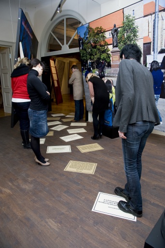 Besucher schauen auf die auf den Boden aufgeklebten Zitatblätter.