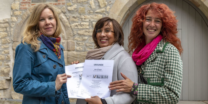 Drei Frauen halten zwei Urkunden in der Hand