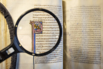 ein mittelalterliche Buch wird durch eine Lupe betrachtet