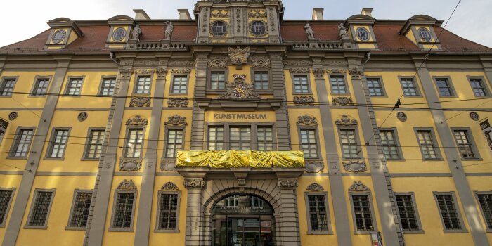gelbes mehrstöckiges Gebäude mit Aufschrift "Kunstmuseum" und einer goldenen Rettungsdecke