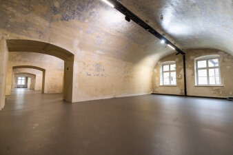 Innenaufnahme eines Gebäudes mit langem Flur und einem großen leeren Raum mit unverputzten Wänden