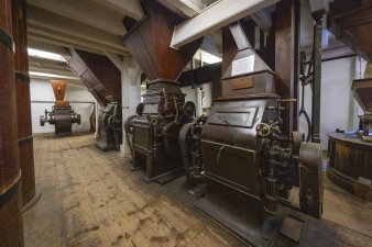 mehrere Maschinen einer Mühle in einem Raum mit Holzboden