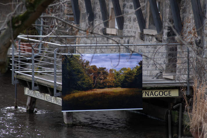 Banner mit Landschaftsbild an einem Zaun über Wasser