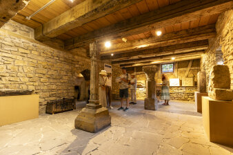 ein Raum im Rohbauzustand mit Holzdecke und verschiedenen Exponaten aus Stein