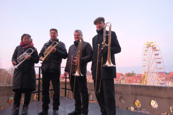 Eine Frau und drei Männer mit Trompeten vor der Kulisse des Erfurter Domplatzes stehend