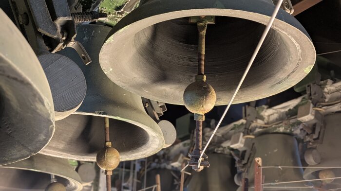Mehrere große Glocken des Turmglockenspiels mit Klöppeln in ihrer Aufhängung im Glockenturm