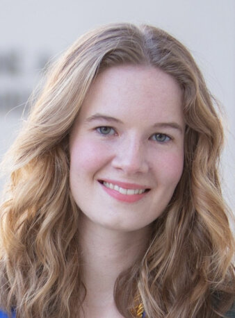 Junge Frau mit blonden, langen Haaren lacht in die Kamera