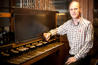 Mann mittleren Alters in kariertem Hemd am Spieltisch eines Carillon-Instrumentes sitzend