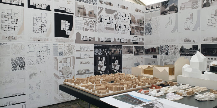 Blick auf Modellarbeiten auf einem Tisch und architektonische Pläne an einer Wand