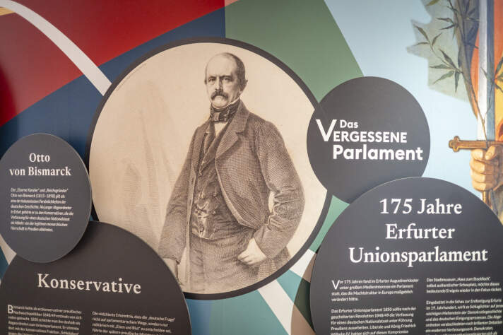 Ausstellungswand mit verschiedenen Texten auf runden Tafeln und einem Bild von Otto von Bismarck