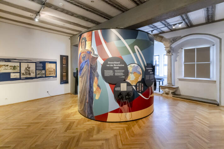 eine kreisförmige Ausstellungsinstallation mit Grafiken, Fotos und Texten