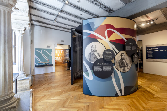 eine kreisförmige Ausstellungsinstallation mit Grafiken, Fotos und Texten