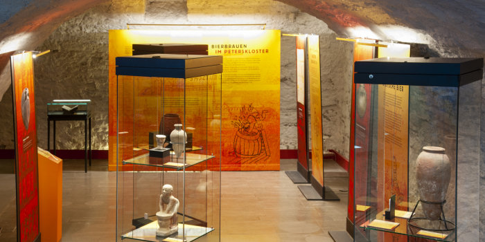 Foto: Sonderausstellungen im Kellergewölbe des Stadtmuseums © Stadtverwaltung Erfurt / D. Urban Beleuchtete Vitrinen mit Objekten in einem Raum mit gewölbter Decke