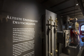 Vitrine mit Ausstellungsgegenständen und Informationstafel "Älteste Universität Deutschlands"
