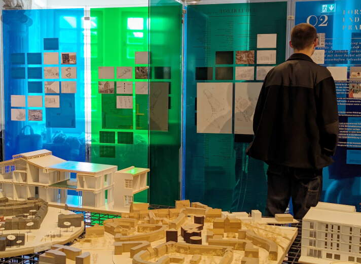 Besucher in einem Ausstellungsraum mit einem Architekturmodell im Vordergrund