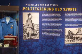 Blaues Banner in der Erfurter Sportausstellung mit DDR Uniform und roter Arzttasche in einer Vitrine