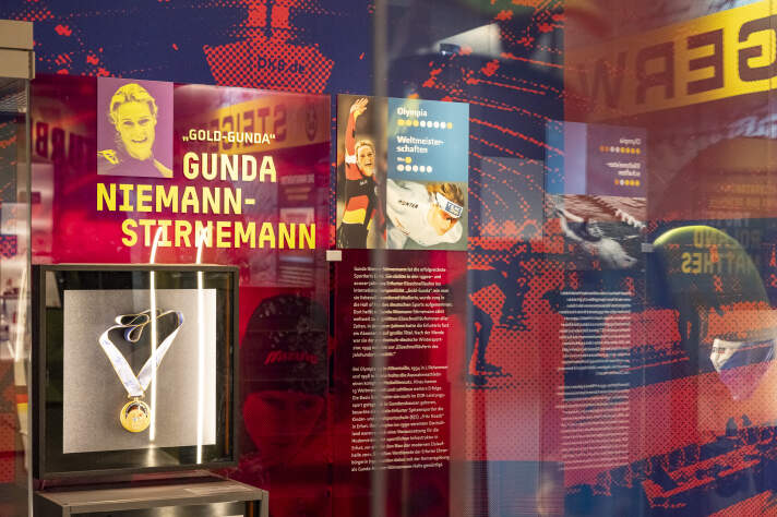 auf einem Zeichenbrett liegt der Lageplan eines Parks, im Hintergrund hängen mit Text und Bild bedruckte Plakate