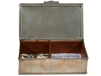 Geöffnete Metallschatulle mit Holzverkleidung innen und einer Trennwand mit Fotos und Schriftstücken.