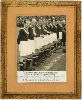Ein Schwarz-Weiß-Foto einer Fußballmannschaft an der Spielfeldlinie auf dem Fußballplatz mit vollem Stadion.
