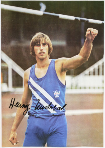 Autogrammbild: Ein Leichtathlet mit blauem Vereinstrikot und blauer Hose greift nach einem Hochsprungstab.