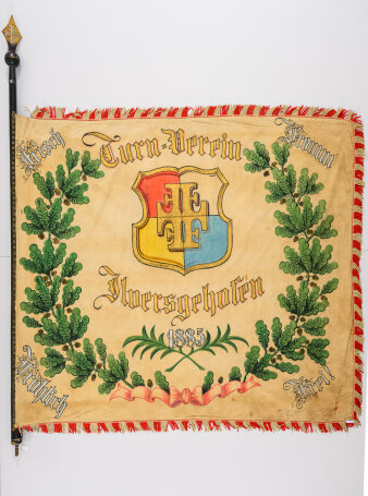 Beige Fahne mit Wappen des „Turn-Verein Ilversgehofen“ umrahmt von einem Eichenkranz und vier Worten