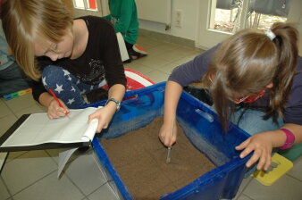 Zwei Kinder bearbeiten Erde in einer Kiste