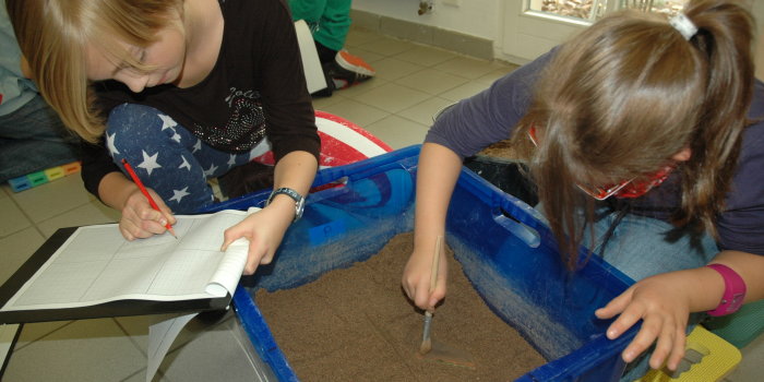 Zwei Kinder bearbeiten Erde in einer Kiste