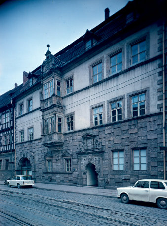 graue Fassade des Gebäudes und zwei parkende Pkws Trabant
