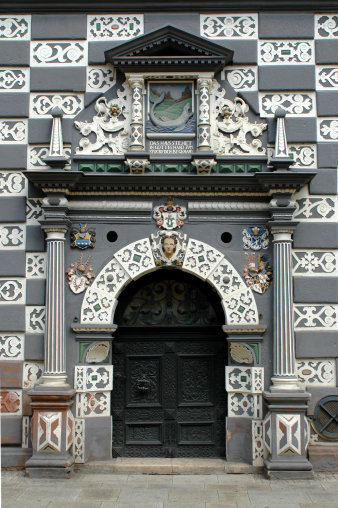 Detailansicht der alten Eingangstür mit Hauszeichen, Stockfisch und Wappen