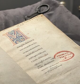 Buchseite einer historischen Handschrift mit einer bunt verzierten Initiale M