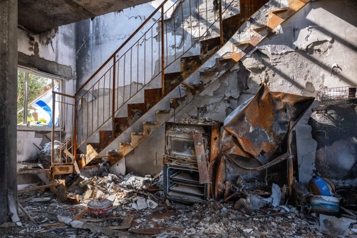 Ein verlassener Raum mit Müll und verrosteten Geräten sowie einer rostigen Treppe.
