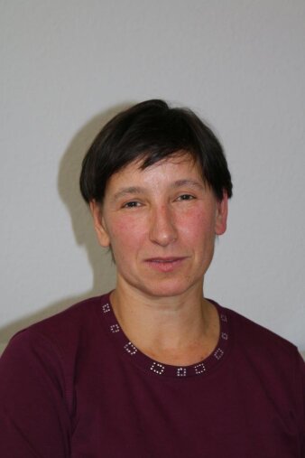 Portrait einer Frau im dunkelroten Oberteil mit kurzen dunklen Haaren