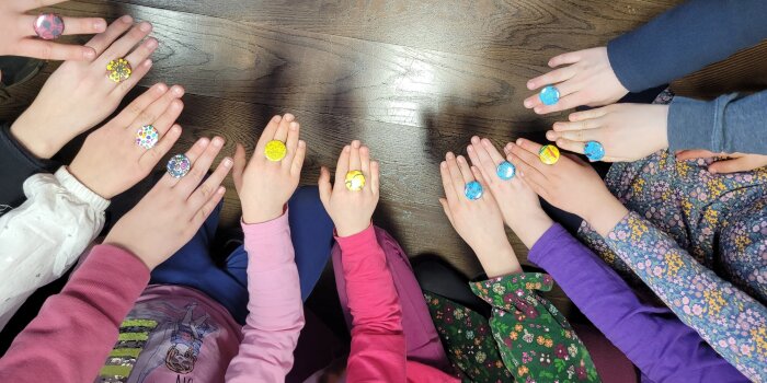 Viele Kinderarme mit Ringen aus bunten Buttons