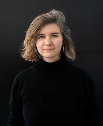Junge Frau in schwarzer Kleidung vor einem schwarzen Hintergrund