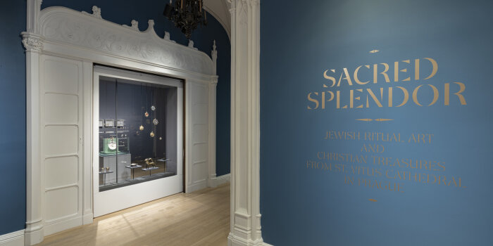 Ausstellungsraum mit dunkelblauen Wänden und einer Glasvitrine mit Schmuckstücken