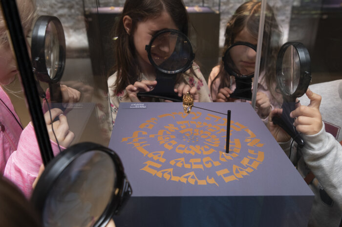 Kinder schauen durch eine Vergrößerung auf ein Objekt in der Alten Synagoge
