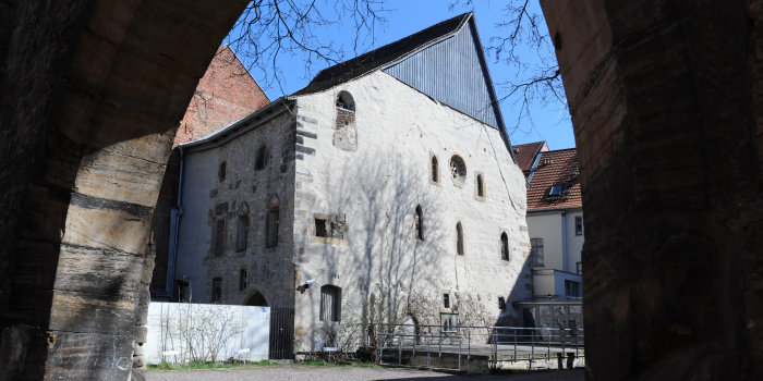 Die Alte Synagoge von der Waagegasse aus gesehen. Im Vordergrund des Fotos der steinerne Torbogen, der auf das Nachbargrundstück führt, von der Synagoge sieht man die Nord- und die Westfassade.