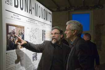 Zwei Männer unterhalten sich vor einer Ausstellungstafel.