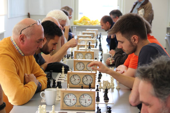 Mehrere Männer sitzen an einem langen Tisch und spielen Schach.