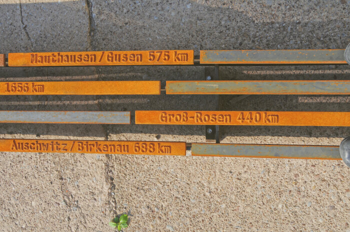 Rostige Metallplatten mit Namen und Maßangaben in km