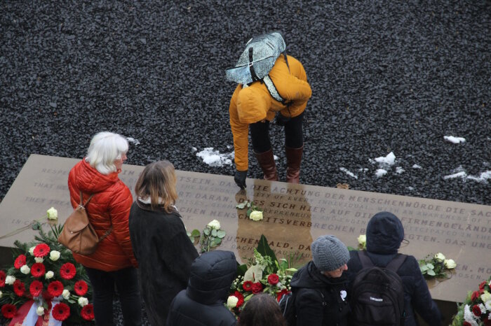 Mehrere Personen an einem Gedenkstein die Blumen niederlegen 