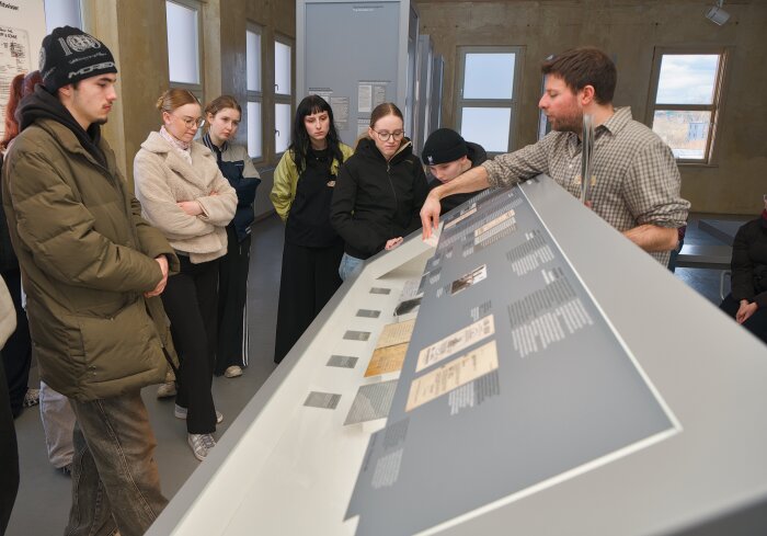 Gruppe von Menschen steht mit Guide an einem Pult in einer Ausstellung