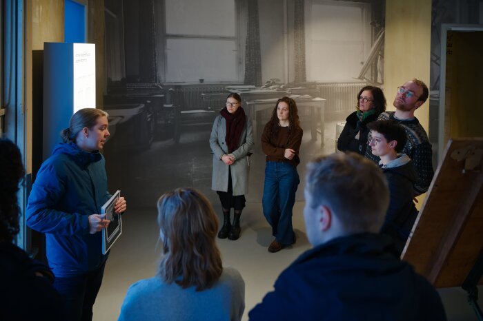 Menschen stehen in Ausstellung während Guide etwas erklärt