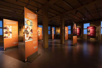 7 Ausstellungstafeln stehen im Raum, an den Wänden hängen weitere Tafeln. 