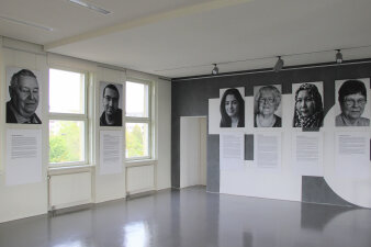 Ausdrucke von Schwarz-Weiß-Fotos und Texten hängen an den Wänden eines Raumes