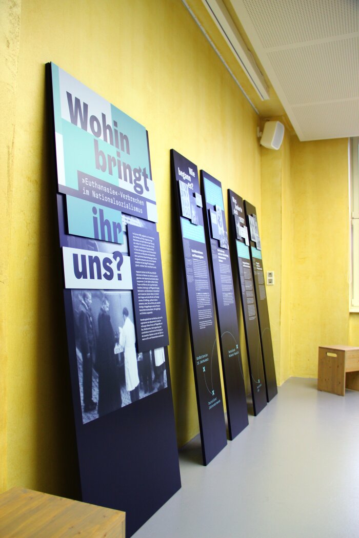 Blick in die Ausstellung "Wohin bringt ihr uns? 'Euthanasie'-Verbrechen im Nationalsozialismus" Gegen eine Wand stehen fünf Tafeln gelehnt.