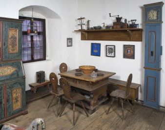 ländliches Wohnzimmer mit einem Tisch, drei Stühlen und blau bemalten Küchenmöbeln 
